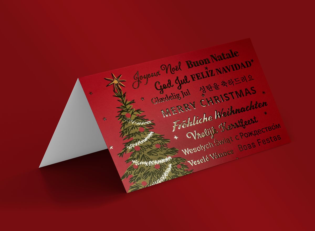 This elegantly designed red Christmas greeting card features a lush green Christmas tree adorned with ornamental decorations and modern geometric shapes. Perfect for sharing festive holiday wishes with family and friends, the card displays multilingual greetings for international appeal. Customize and print your own personalized Christmas greeting card with Sprint24's online printing service.