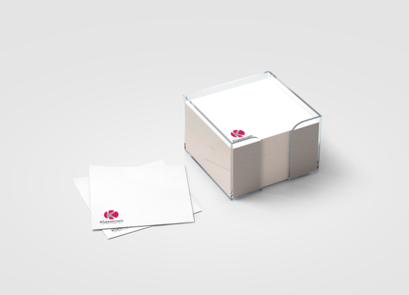 Custom paper cube block notes with a company logo printed on each sheet, displayed in a transparent acrylic holder alongside loose sheets. Sprint24 prints personalised paper cubes of 500 sheets in 10x10 cm format — a versatile office gadget or promotional gift for clients and employees.