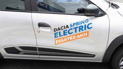 Professional business sticker applied to a white Dacia Spring Electric vehicle, demonstrating custom promotional messaging for fleet branding. Business car stickers like these deliver high-visibility advertising on vehicles, perfect for corporate campaigns and automotive promotional visibility. Custom-printed decals ensure professional quality printing with guaranteed durability on vehicle surfac…