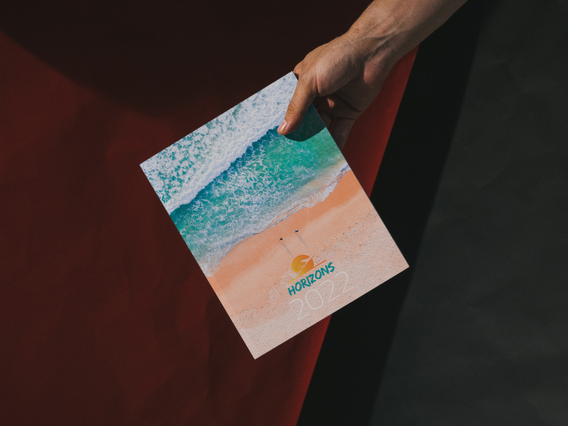 Hand holding Horizons thread-sewn weekly agenda with aerial beach. Hand holding Horizons thread-sewn weekly agenda with aerial turquoise ocean and beach cover. 128 pages Sprint24.