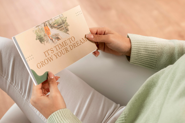 A person holding a landscape-format custom postcard printed with the motivational message 'It's Time to Grow Your Dreams' over a garden scene photograph on a warm beige background. Custom postcards printed in landscape format are an effective and versatile marketing tool for promoting lifestyle brands, wellness events, garden centres, coaching services and product launches.