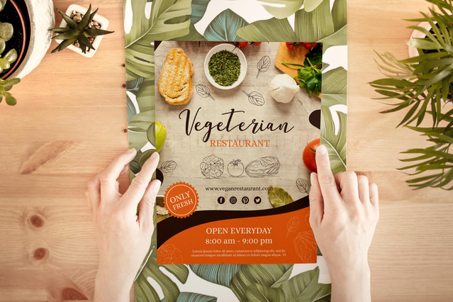 Two hands opening a 'Vegetarian Restaurant' eco flyer with fresh food photography on a wooden table surrounded by tropical plants. Sprint24 prints ecological flyers and postcards on natural or recycled paper — ideal for restaurants, vegetarian brands and eco-conscious businesses looking for sustainable printed marketing materials.