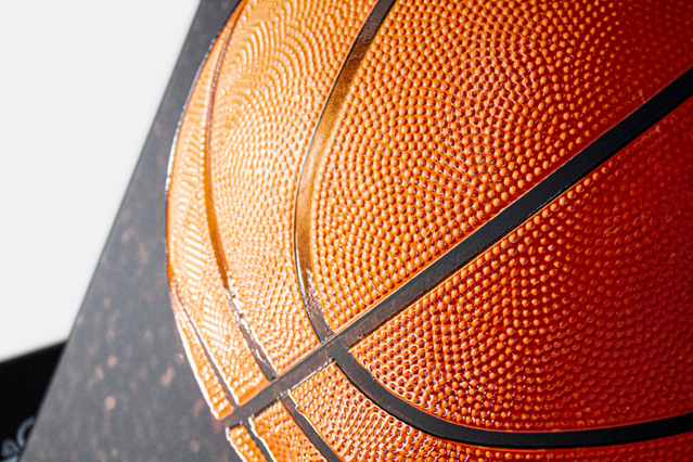 Macro close-up basketball orange textured surface with black seam. Macro of basketball orange pebbled texture and black seam lines showing fine tactile surface detail. Sprint24.