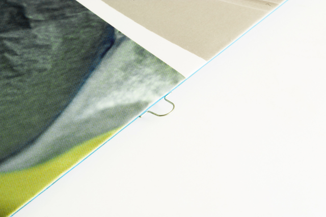 Close-up view of an omega staple binding, showing the distinctive metal staple spine that secures book pages together. Ideal for professional booklets, catalogs, and bound documents requiring durability and a polished finish. Perfect for custom print projects seeking reliable binding solutions.