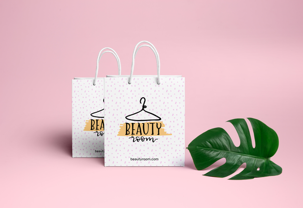 Elegant white paper shopping bags with white rope handles and minimalist hanger line artwork. These laminated, UV-coated bags deliver premium quality for fashion boutiques, clothing stores, and beauty retailers. Customize your personalized shopping bags with your own branding and design.