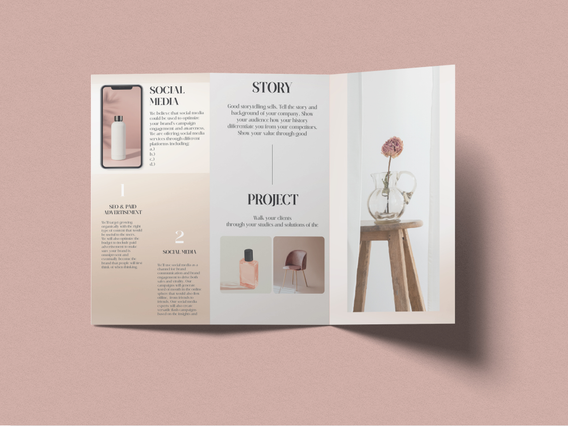 An open cream and blush pink tri-fold brochure with 'Social Media', 'Story' and 'Project' panel headings, a phone mockup and a decorative glass vase with a dried flower on a wooden stool. Custom-printed tri-fold leaflets in soft lifestyle tones are ideal for marketing agencies, photographers, wellness brands and creative professionals promoting services and social media packages.