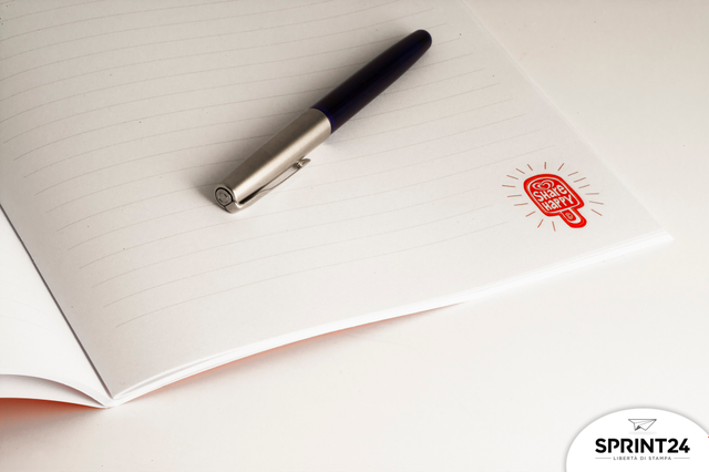 Premium stapled notebook displaying bright white coated pages and quality paper construction ideal for professionals. The interior view reveals the signature red branding, double metal staple binding, and matt lamination finish that define this corporate gift and office product.