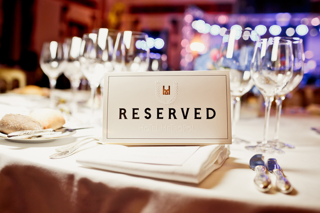 Elegant white reserved table placeholder card displayed on formal restaurant setting with sophisticated typography and decorative crown. Perfect for restaurants, catering, and dining establishments to mark reserved seating and enhance table ambiance.
