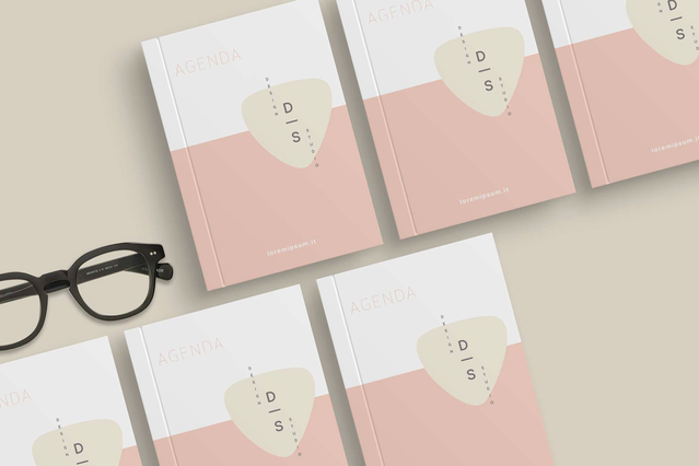 Stack custom threadbound agendas pink minimal cover design and glasses Five custom threadbound agendas with pink minimalist D|S branded cover on beige surface Sprint24.