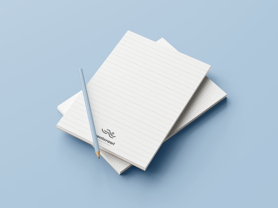 A stack of white custom A5 notepads with a lined template and Sprint24 logo at the bottom corner, displayed with a pencil on a light blue background. Custom A5 notepads with lined, squared, dotted or millimetre templates are practical corporate promotional tools ideal for companies to distribute to clients, employees and partners at meetings, trade fairs and events.