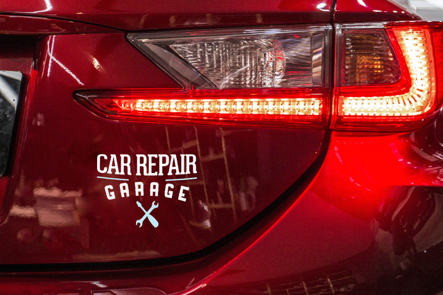 A white pre-spaced vinyl decal reading 'Car Repair Garage' applied to the rear of a red car next to the tail light. Sprint24 prints custom pre-spaced vinyl decals on glossy white vinyl with up to 60 months durability — ideal for vehicle branding, shop windows and signage with clean, bubble-free dry application.